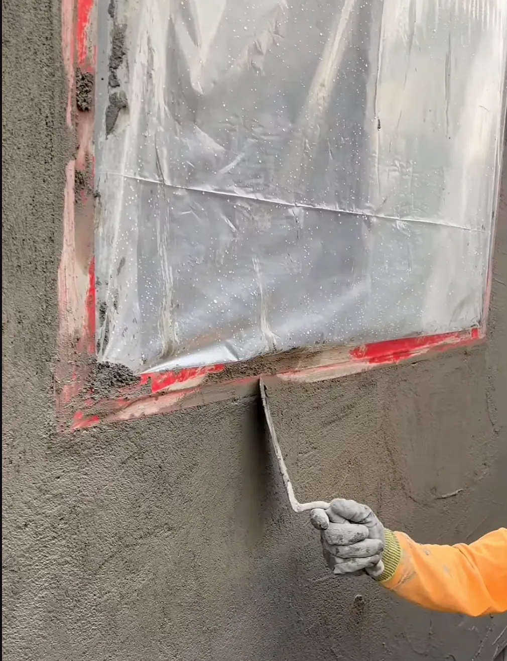 Man with orange shirt applying new stucco around a window