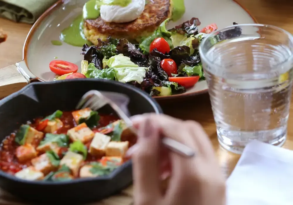 Close-up of a meal with salad, a vegetable dish, and a glass of water on a table.