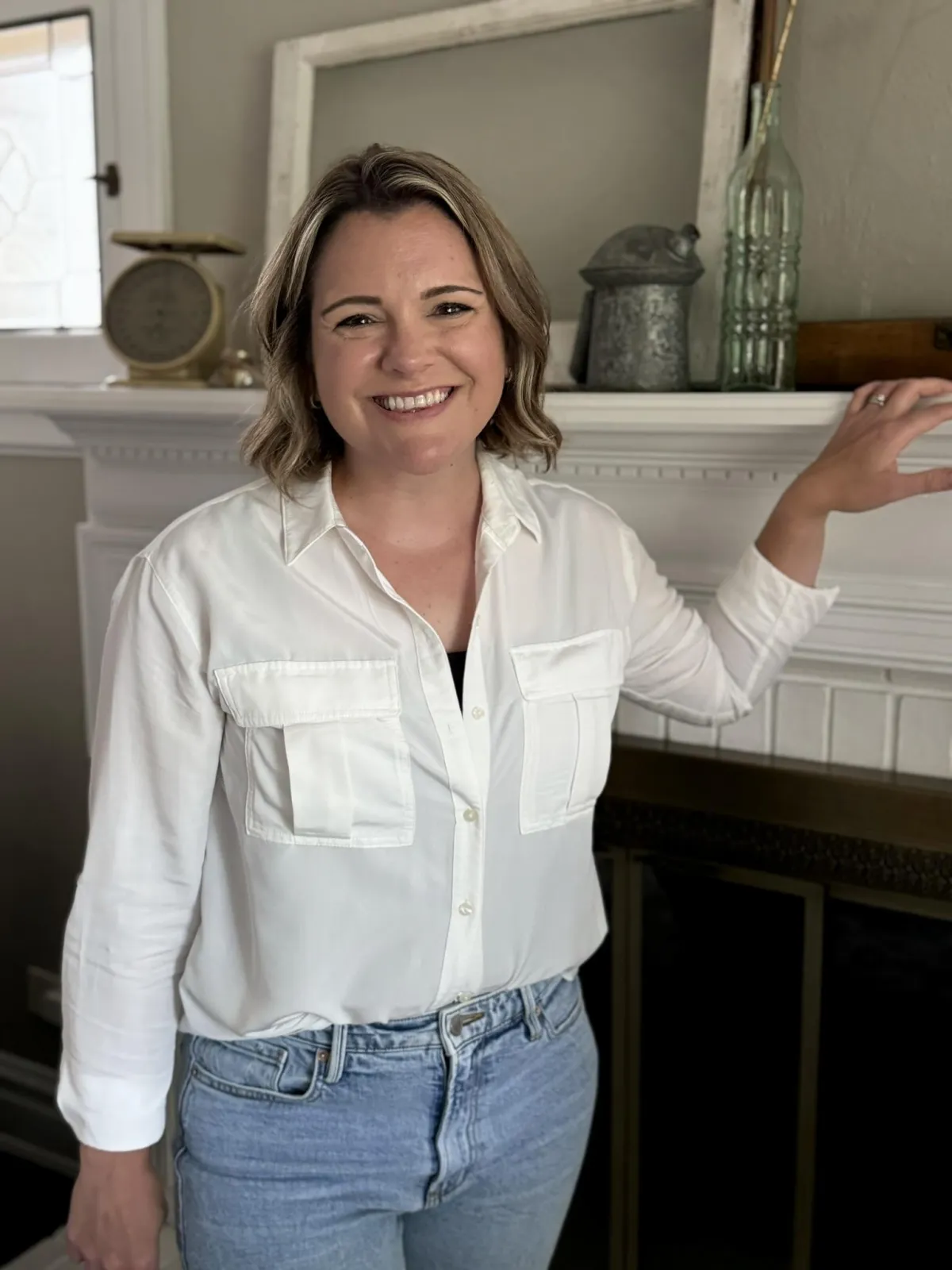 maternal mental therapist standing at fireplace mantle with warm smile