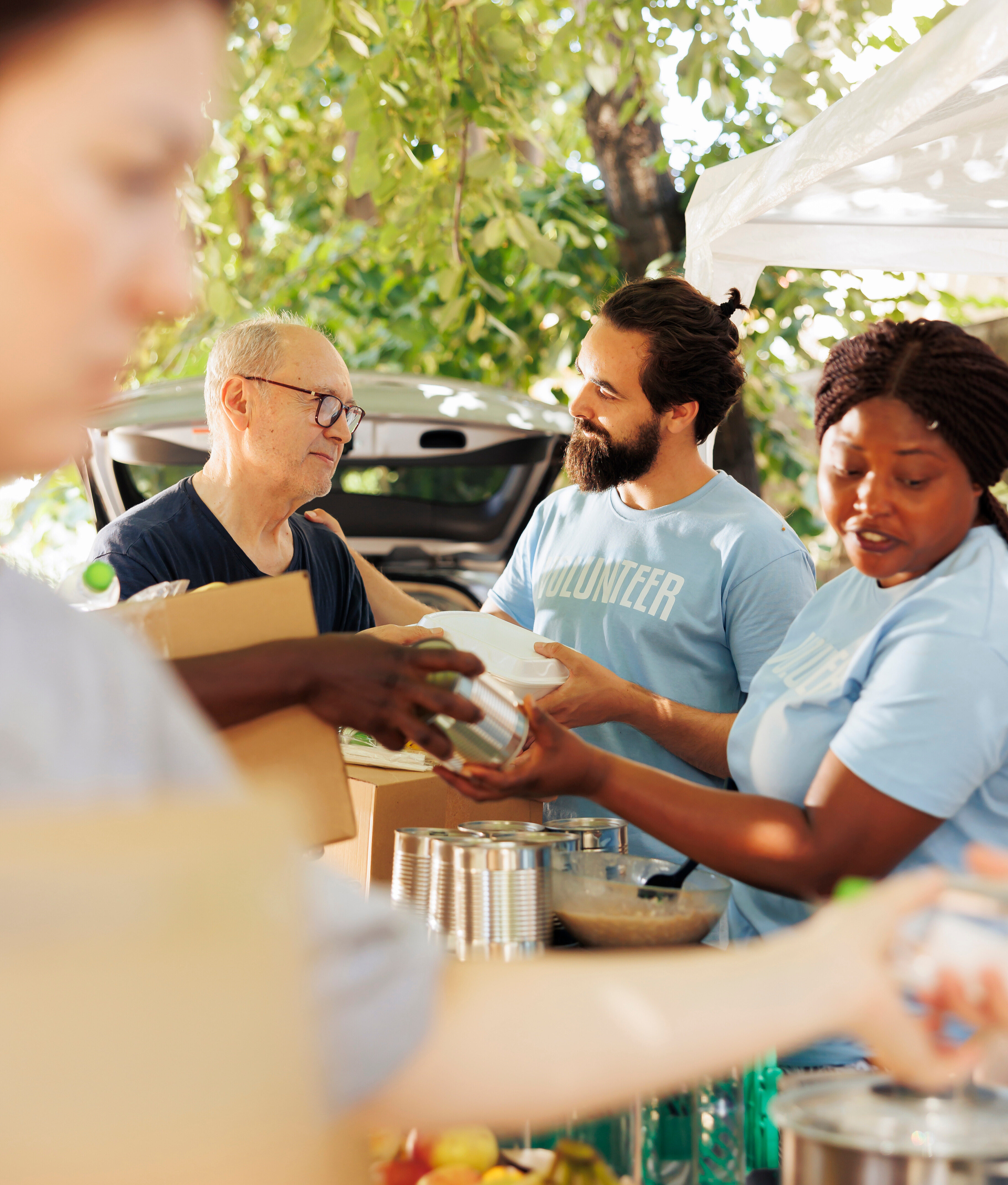 Volunteers serving food and handing out meals to people at an outdoor community event.
