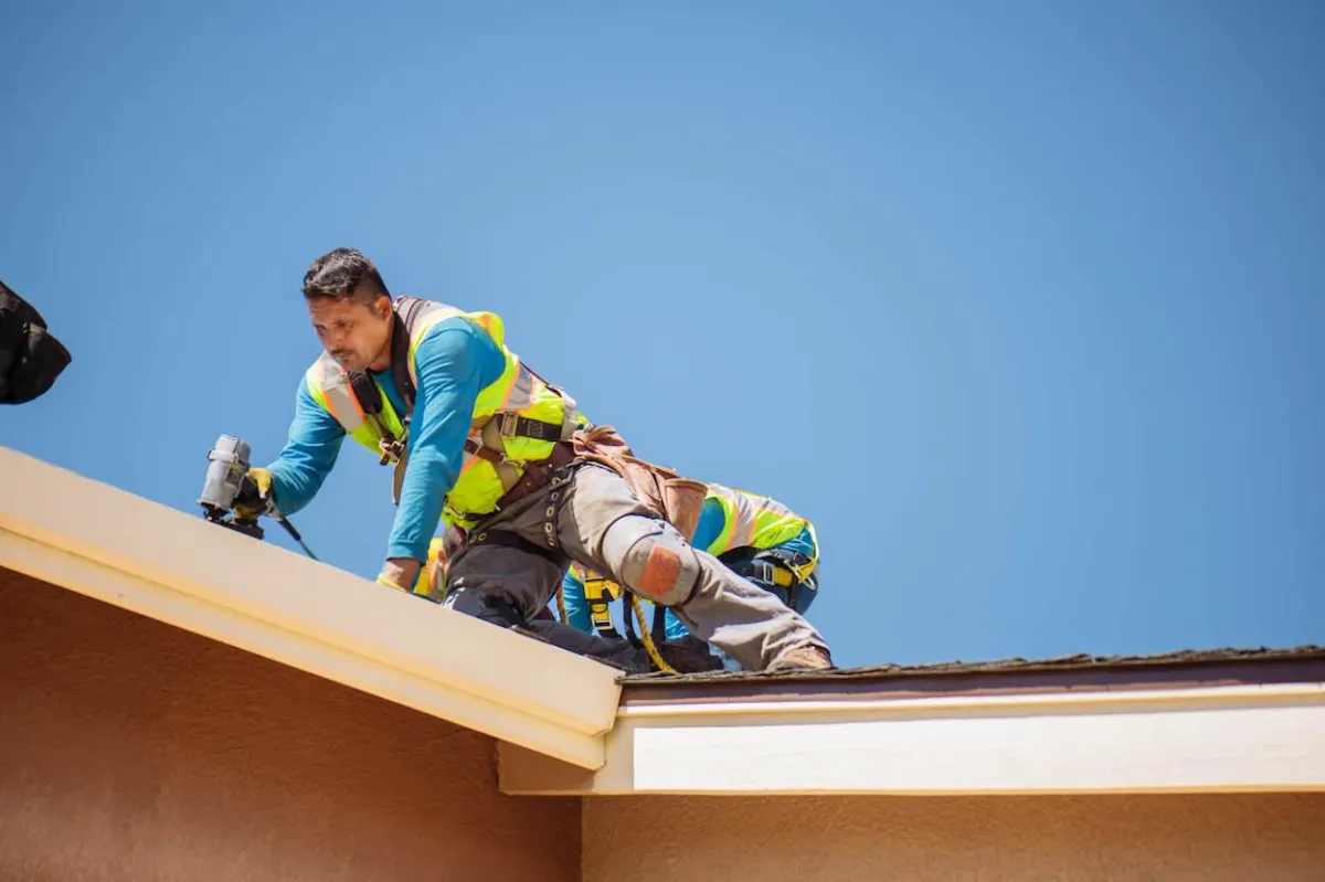 a man in a yellow shirt is working on a roof