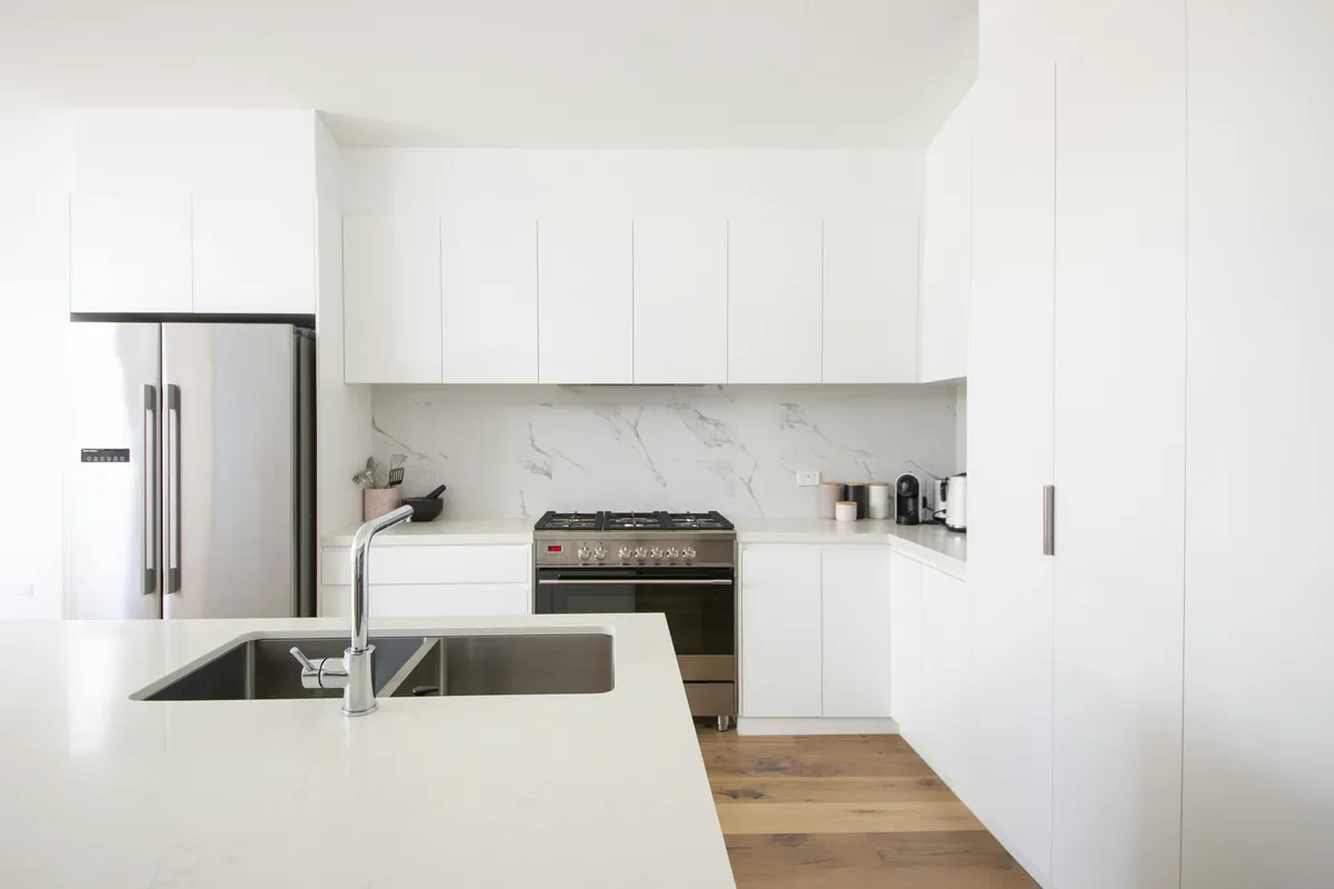 Spotless white kitchen with clean countertop and glossy cabinets