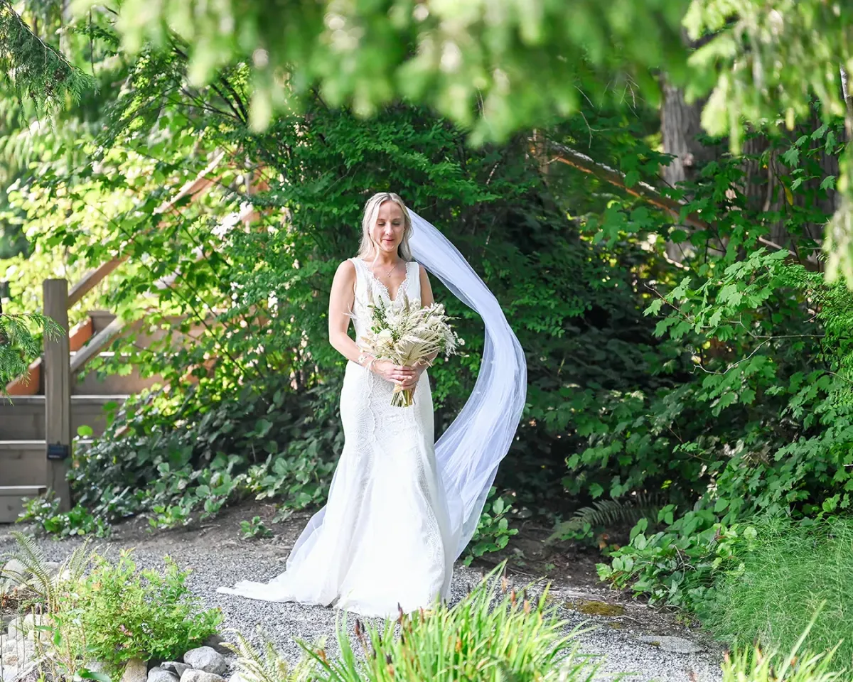 Bride walking beside the pond with her veil blowing in the wind at Gray Bridge Venue.