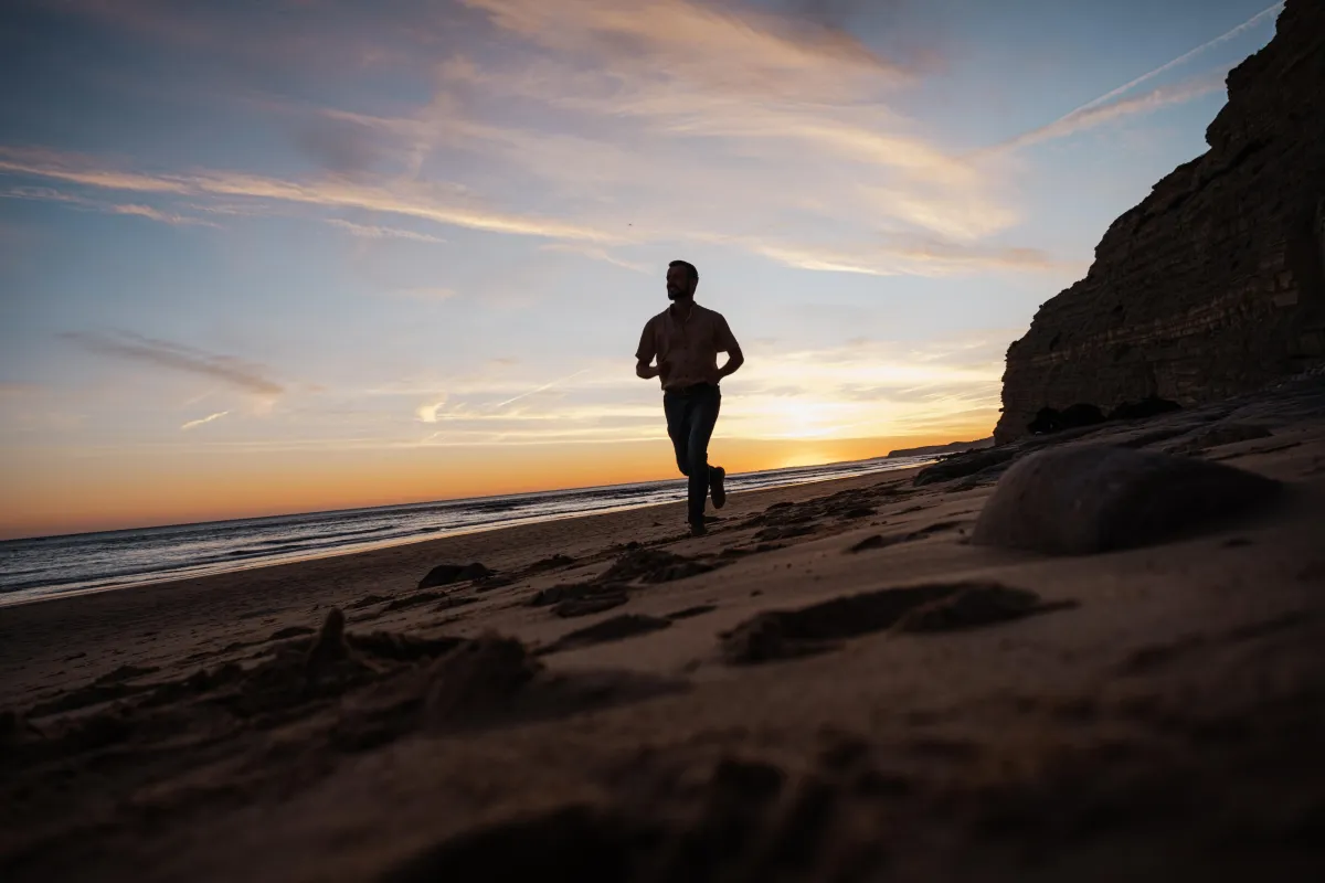 „Mann joggt am Strand bei Sonnenuntergang – Breathwork, Bewegung und Verkörperung für innere Transformation