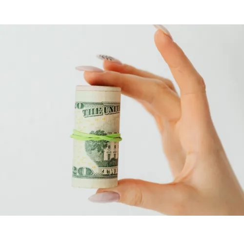 Hand holding a roll of money that is held together by a rubber band.