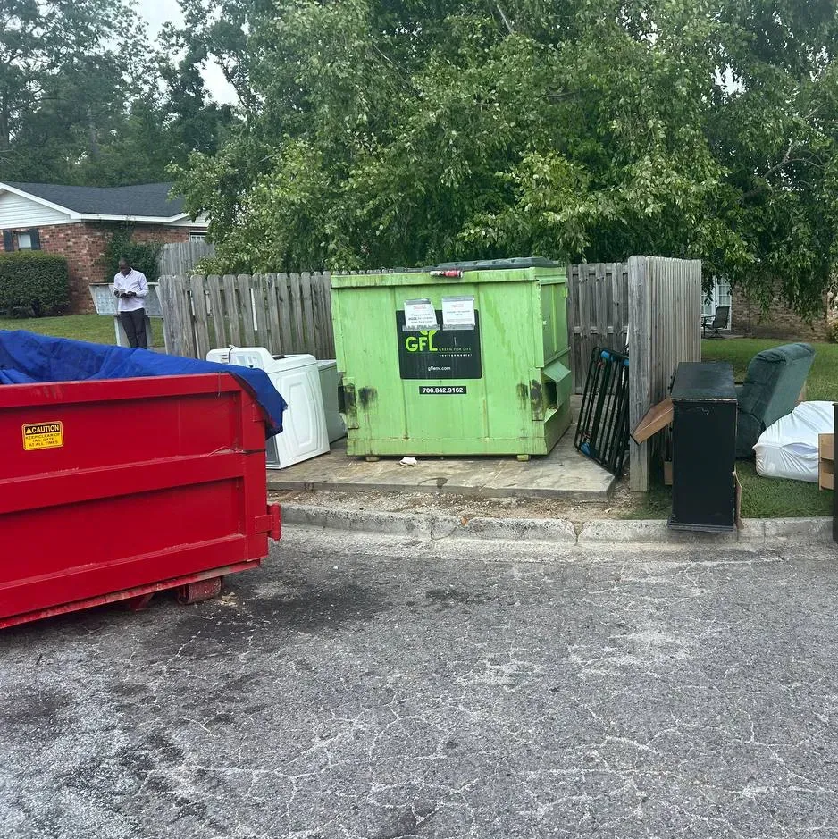 Row of large dark wheeled bins on gravel