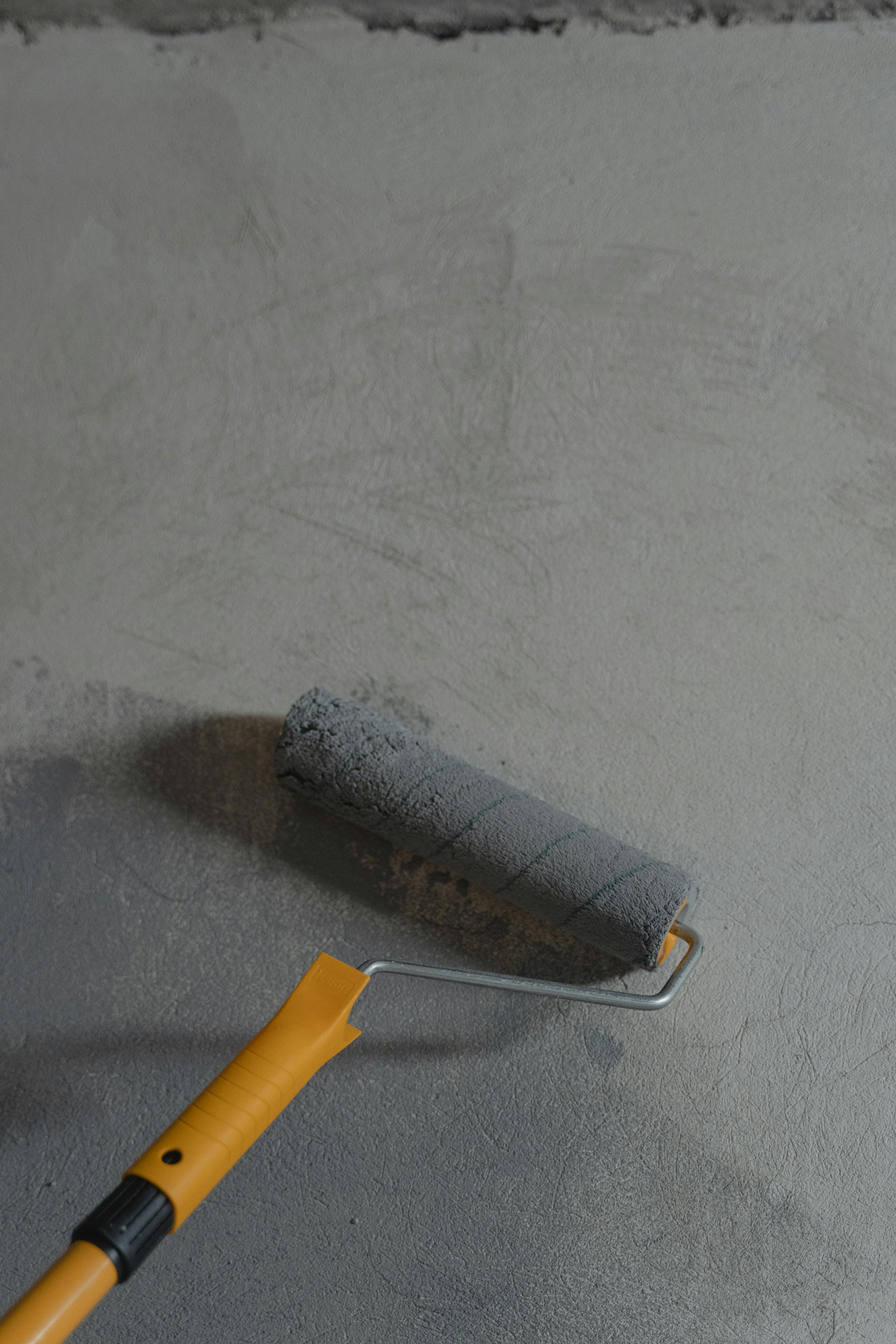 roller rolling grey epoxy onto concrete surface
