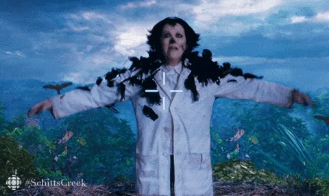 Moira Rose from Schitt's Creek covered in crows with arms outstretched in The Crowening