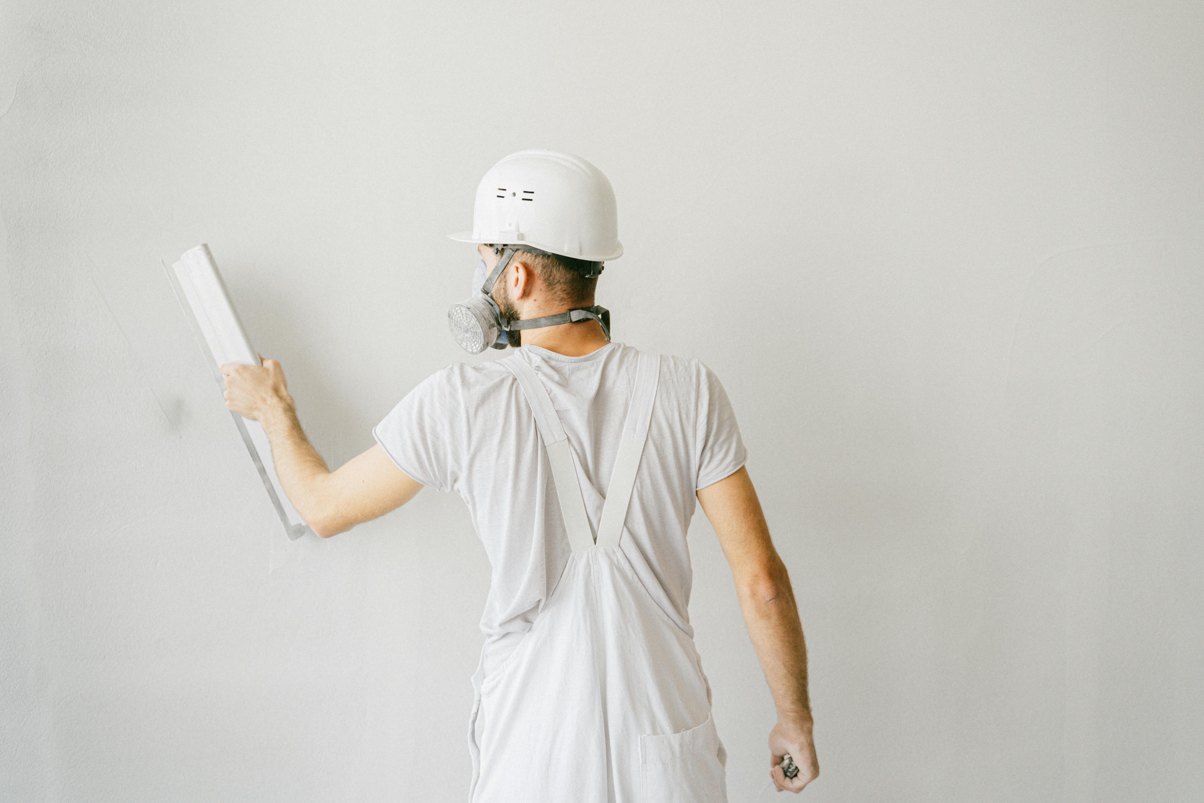 white shirt man painting wall white