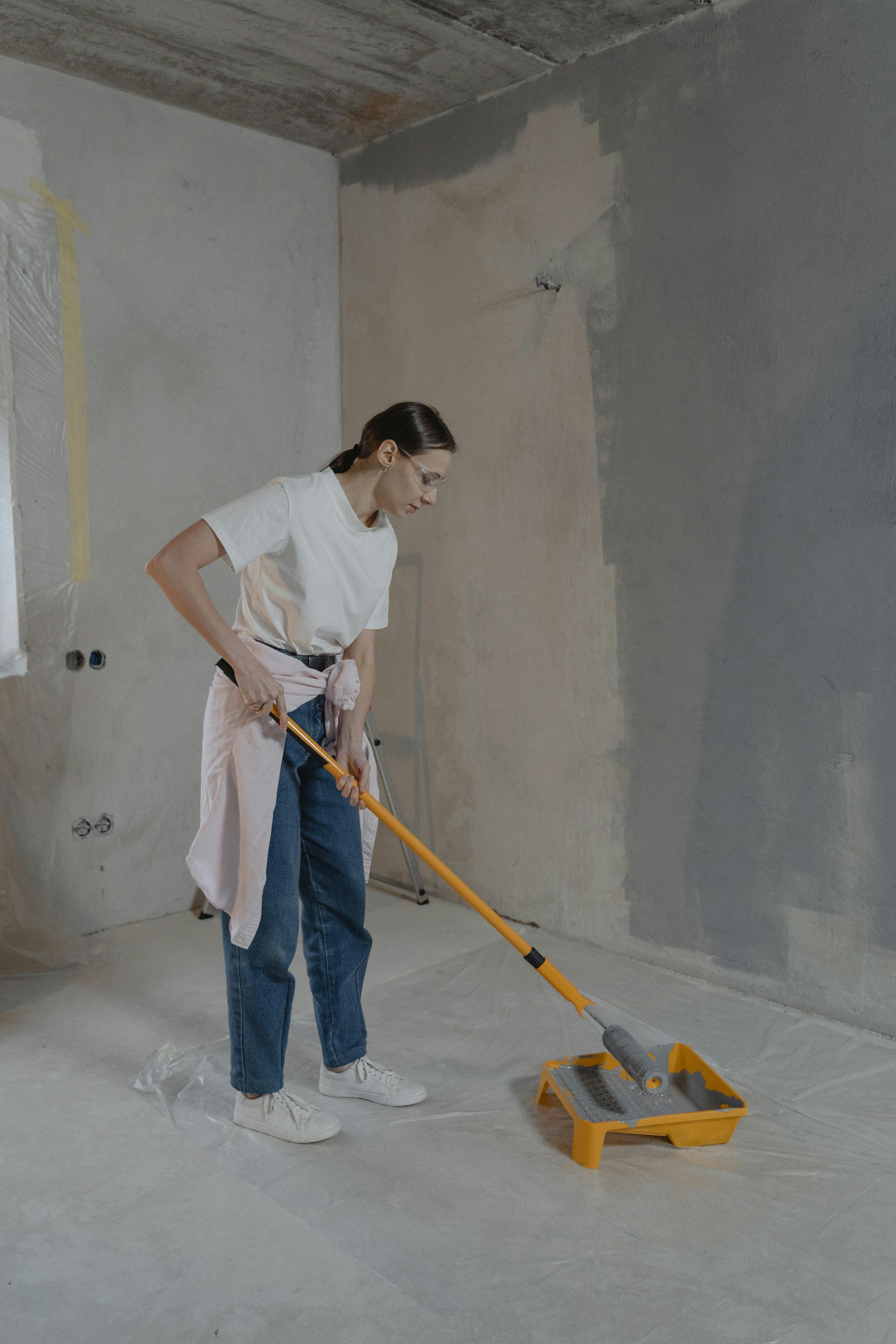girl topping up grey paint onto roller