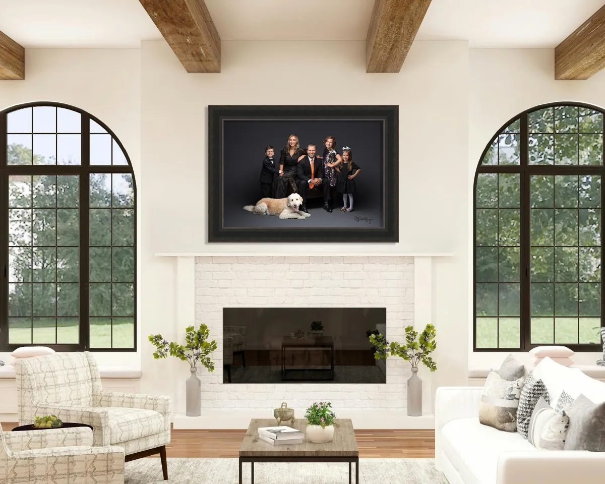 Formal family studio portrait of a father in a black suit with orange tie, mother in a beaded black gown, and three children in formal attire. A large cream-colored Goldendoodle dog lies in the foreground against a dark gray backdrop.