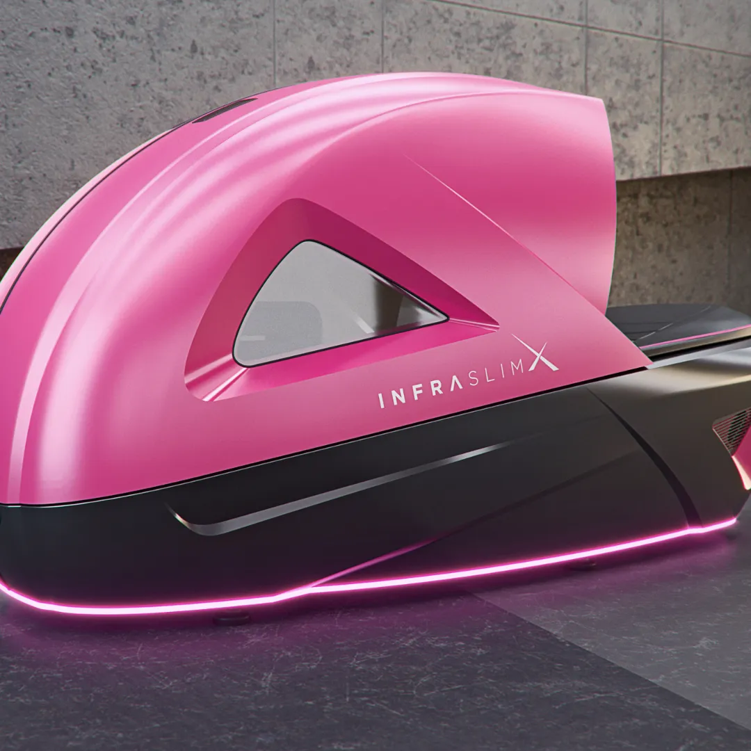 InfraslimX machine in a vibrant pink and black design with glowing LED lights at the base. The top part of the machine is open, showcasing the interior. The ‘INFRASLIMX’ logo is visible on the side.