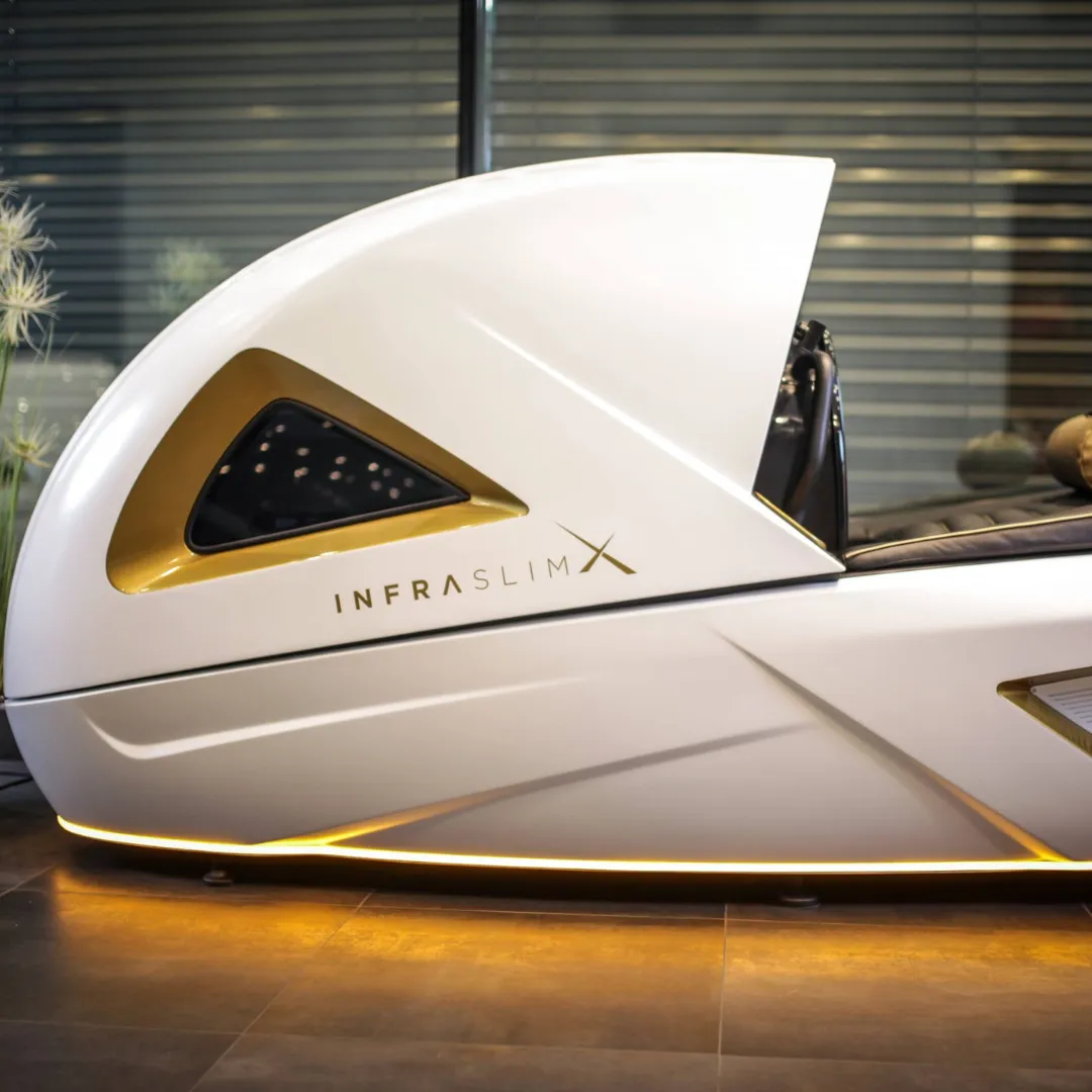 InfraslimX machine with elegant gold accents, sleek curves, and ambient lighting, designed for high-end fitness and wellness treatments.