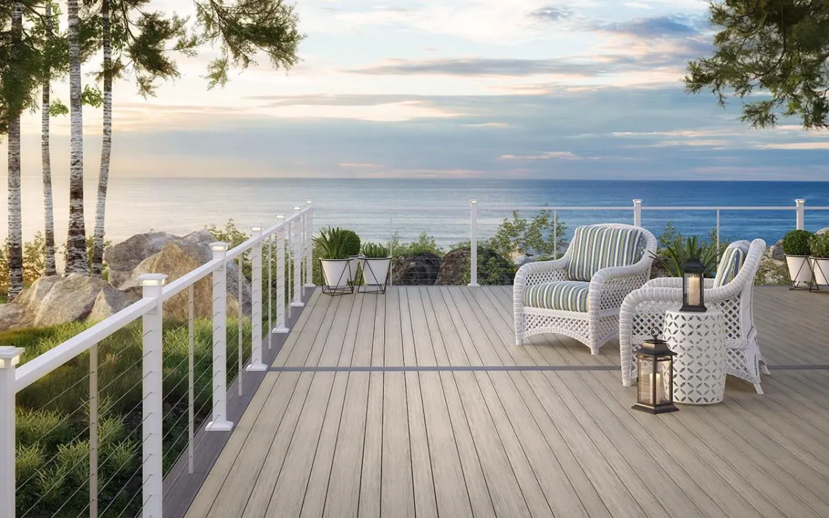 Coastal deck design with white wicker chairs, ocean view, and minimalist plant decor.