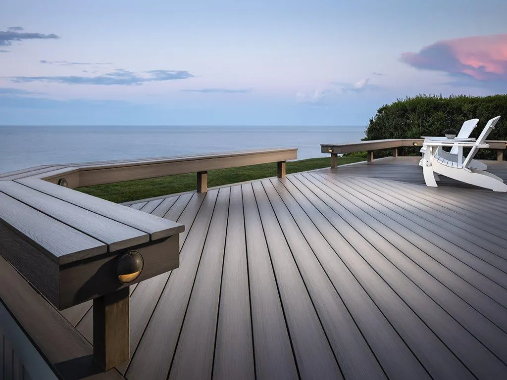 Elegant beachfront deck with modern lighting and lounge chair, perfect for evening relaxation by the sea.