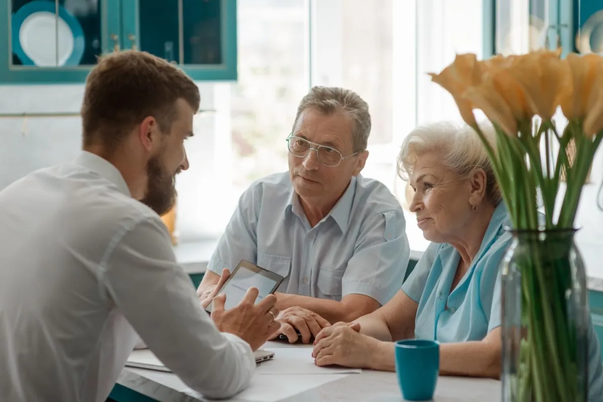 Consultant discussing financial planning with senior couple, emphasizing personal client care.