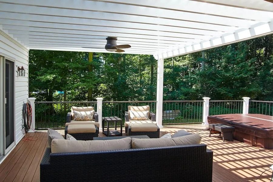 Spacious wooden deck with pergola offering cozy seating and hot tub for outdoor relaxation and entertainment.