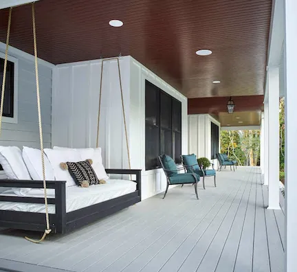 Cozy porch with a swing and seating area showcasing stylish decking and ceiling design.