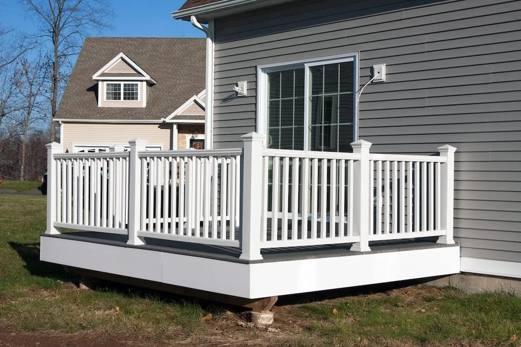 White vinyl railing surrounding a spacious grey deck attached to a modern home exterior, showcasing stylish and secure deck design options.