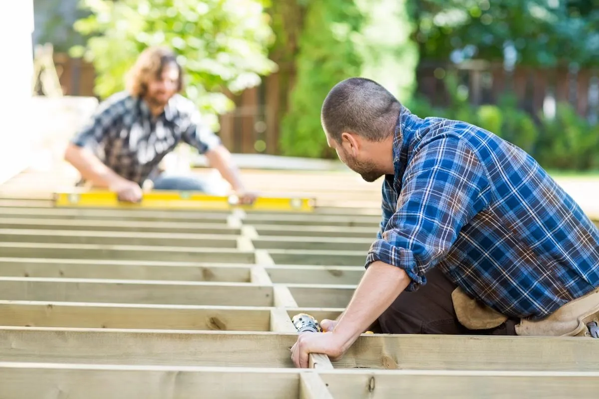 Professional deck builders working with precision on new deck construction for home improvement.