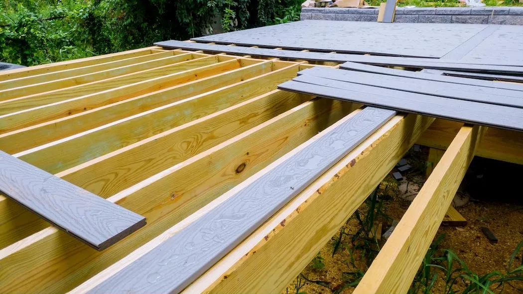 Detailed view of a deck under construction highlighting the precise installation of wooden beams and composite deck boards.
