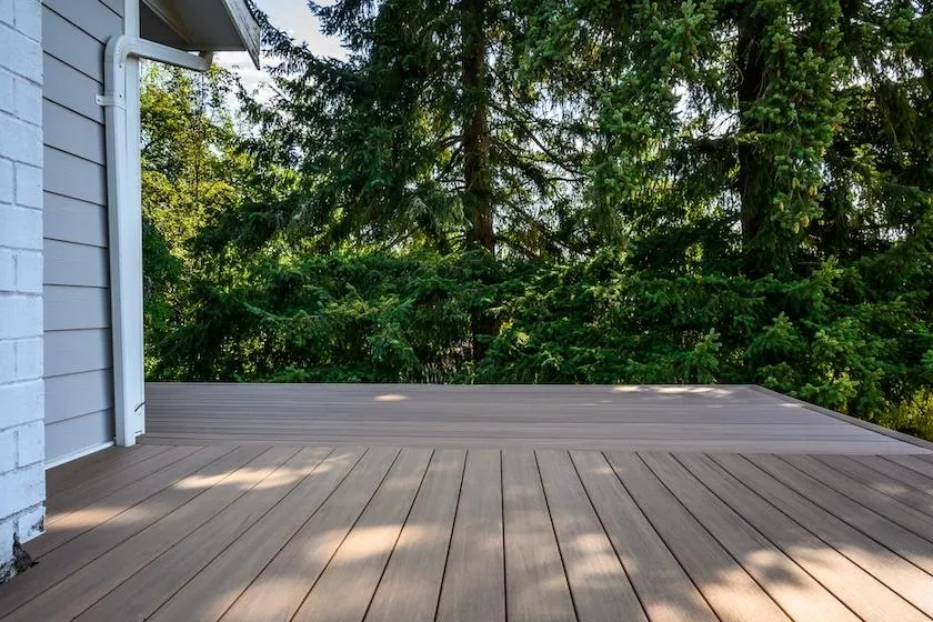 Spacious and modern brown deck installation by Skyline Decks surrounded by lush greenery, enhancing outdoor living spaces.