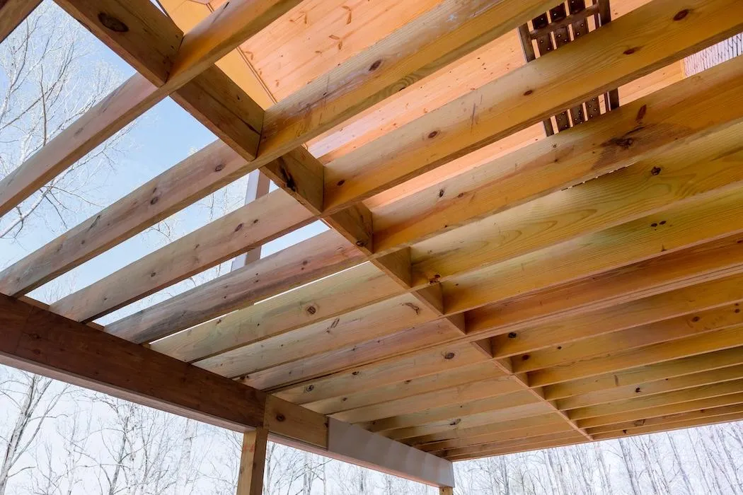 Underneath view of a newly constructed wooden deck showing the sturdy craftsmanship and natural wood patterns, ready for outdoor living enhancements.