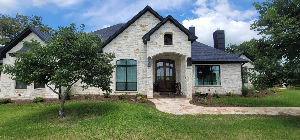 Professional window cleaning and pressure washing by Shinetime Solutions on luxury stone home with crystal clear windows and clean driveway