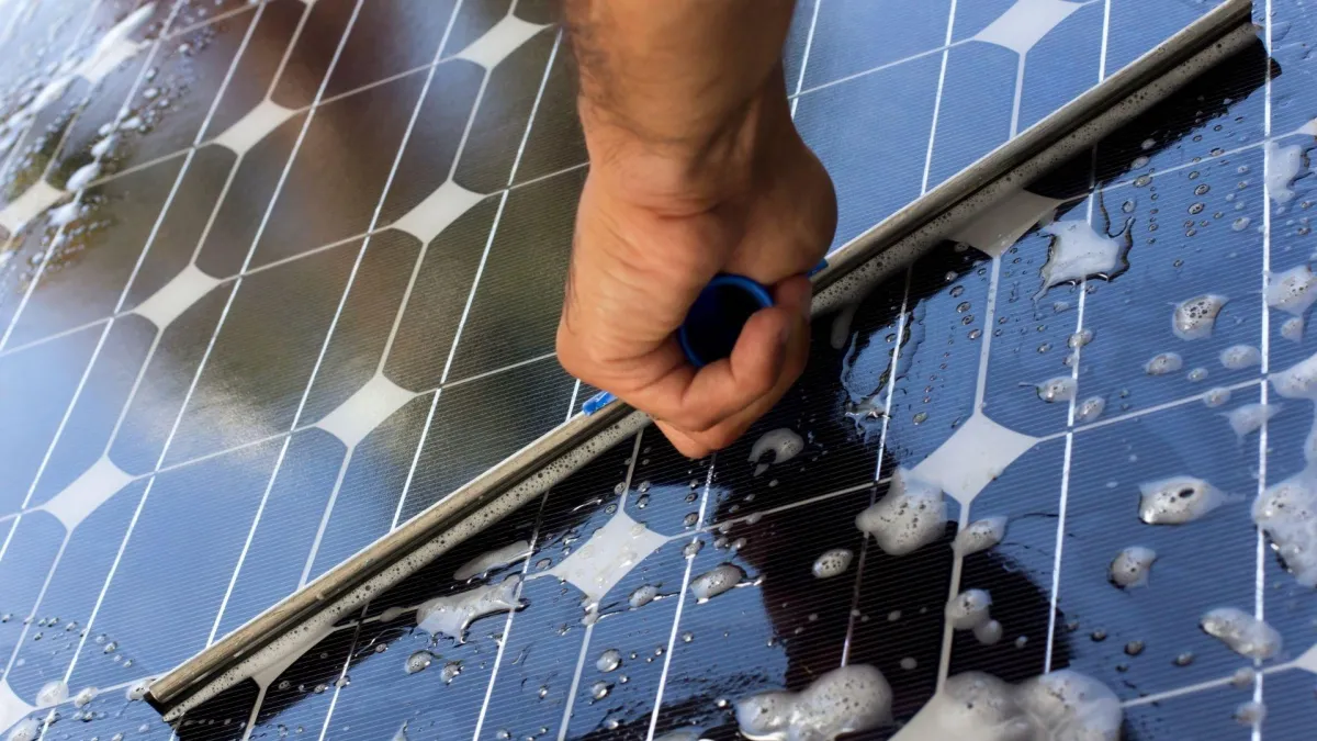 "Professional solar panel cleaning by Shinetime Solutions showing hand cleaning technique to maximize energy efficiency