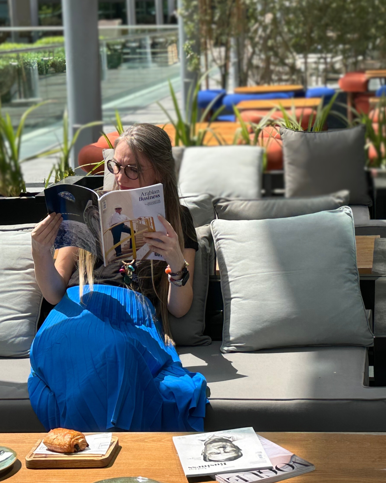 Martina Kikic reading Arabian Business magazine outdoors in Dubai — LinkedIn strategist and personal branding expert