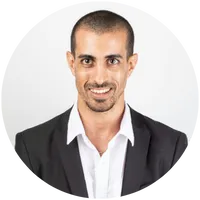 Professional headshot of a confident man in a suit with a clean-cut style, smiling in front of a white background. Ideal for LinkedIn, business branding, or executive bio.