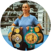 Female champion athlete posing confidently in a boxing ring with WBC and other world title belts. A powerful image of success, leadership, and discipline in sports.