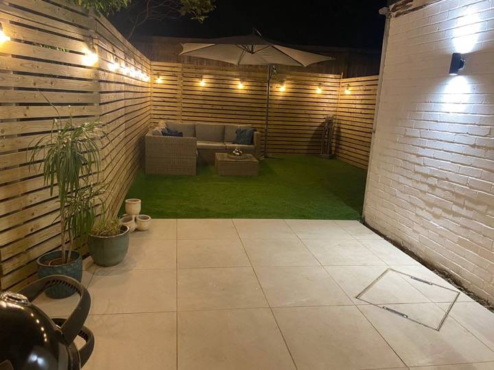 Night garden with patio, artificial grass and festoon lighting — completed garden project in Reading