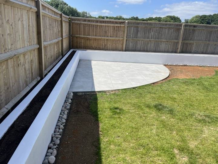 Curved porcelain patio with white raised planting beds — landscaping project in Reading