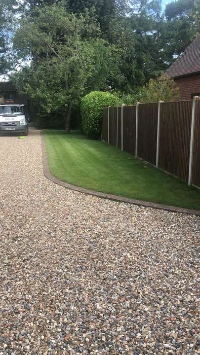 Gravel driveway with turf strip and brick edging along fence line — driveway project in Berkshire