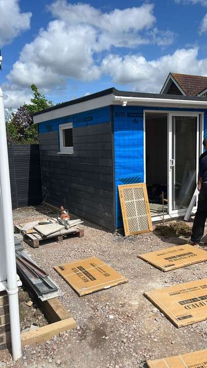 Garden office build in progress with dark cladding and sliding doors — garden room installation in Berkshire