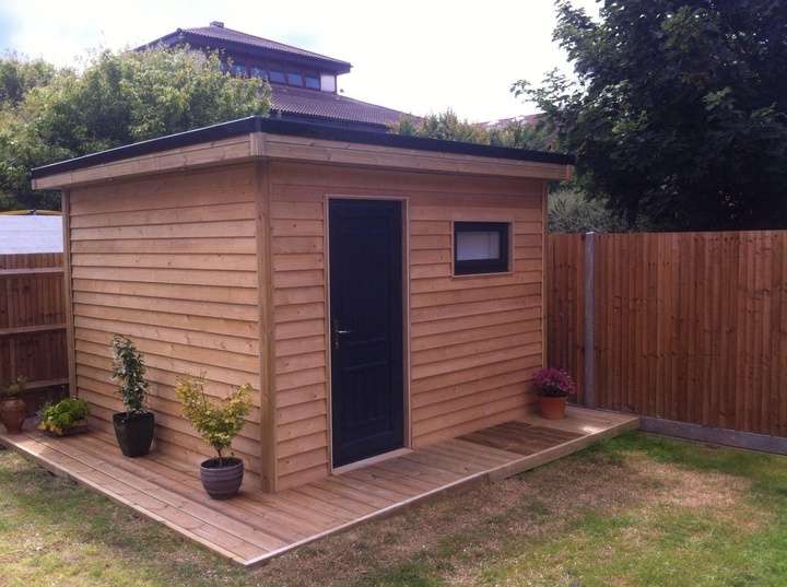 Completed timber-clad garden office with flat roof and decking step — garden room installation in Berkshire