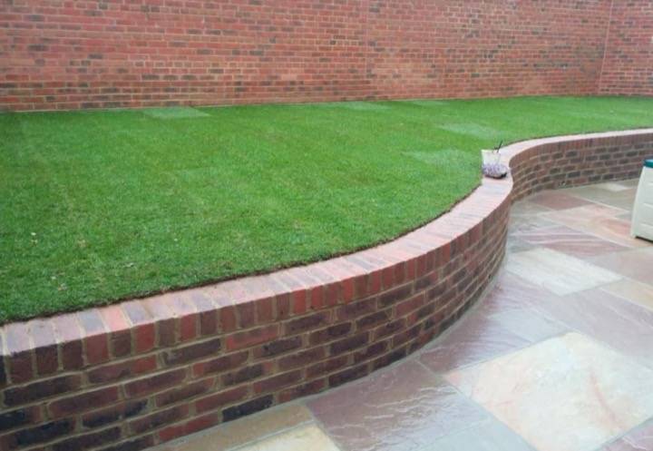 Turf lawn with brick curved retaining wall and sandstone patio — garden project in Berkshire