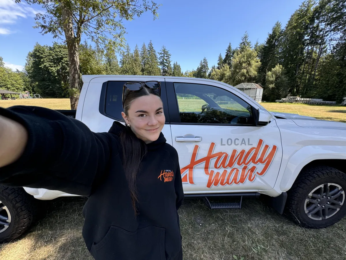 Entrepreneur Jade Sprake smiling in a red top, standing in front of large windows with city buildings in the background.