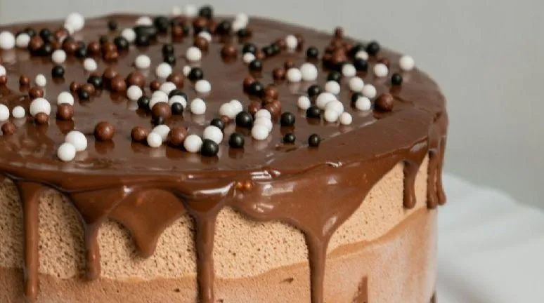 Close-up of a chocolate drip cake with pearl sprinkles, handcrafted for a custom celebration.