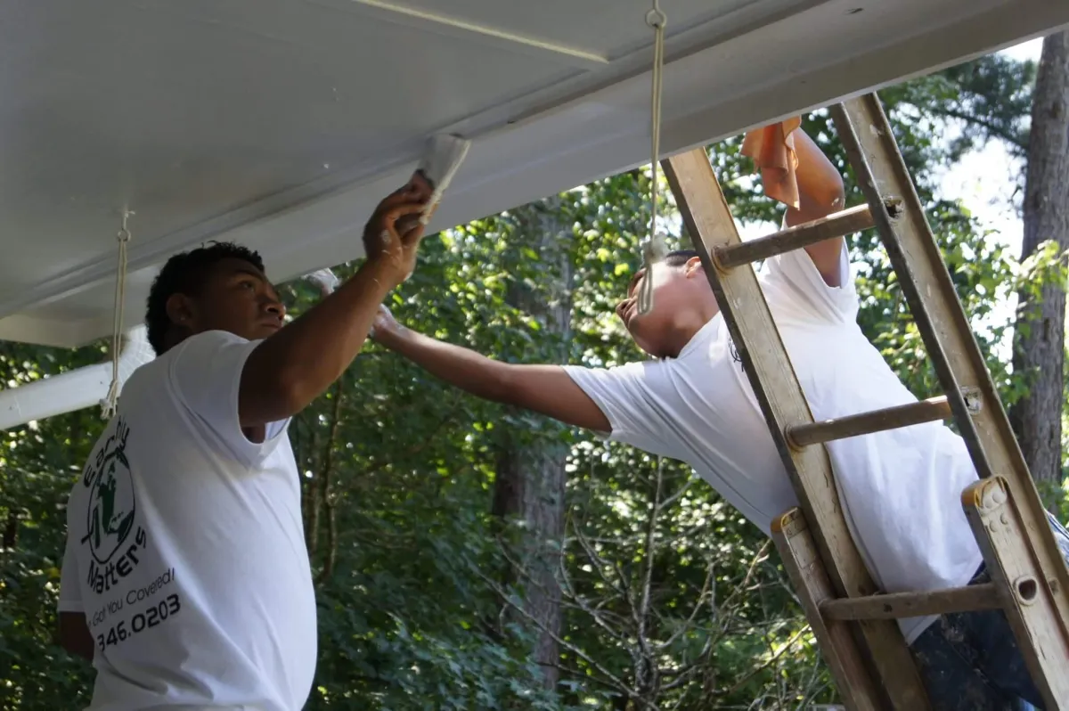 A close-up of an Earthly Matters technician carefully using a tool to remove old, cracked caulk from a porch roof in Alpharetta.