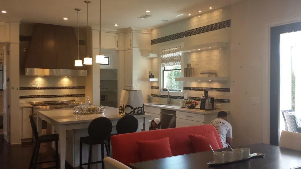 Bright, modern kitchen with white cabinets and a red sofa, showcasing a professional interior painting project by Earthly Matters.
