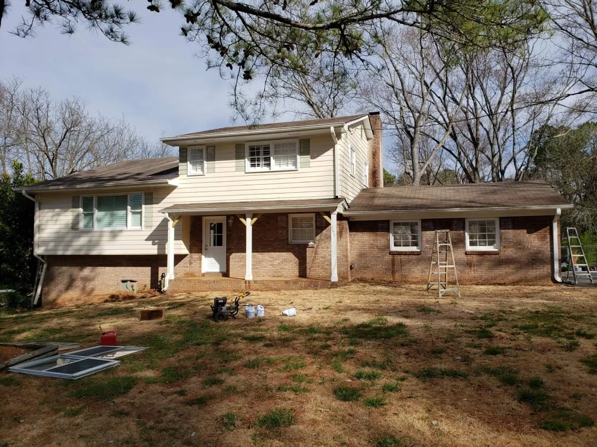 Split-level home with a mix of tan siding and red brick, showing its appearance before a major exterior update