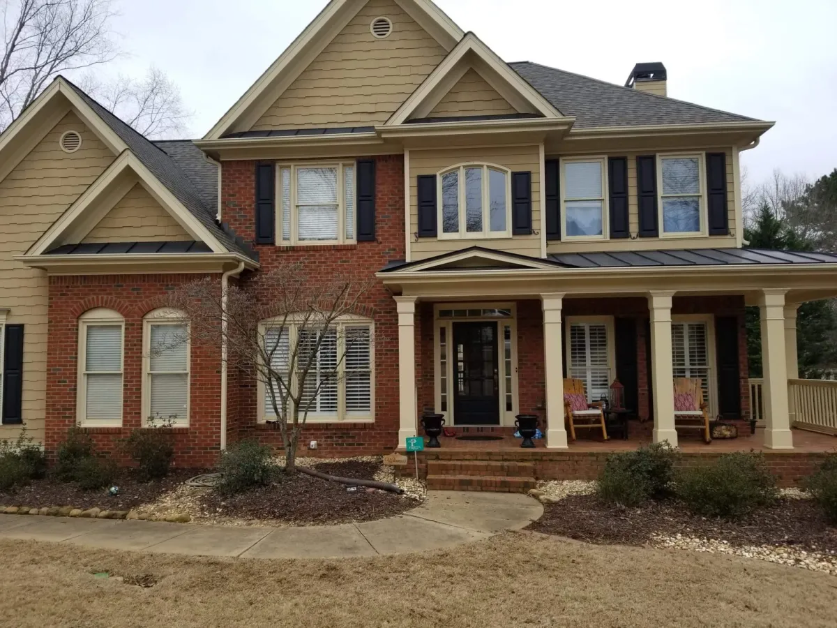 Classic two-story home with red brick and tan siding, appearing dated before its exterior painting project.