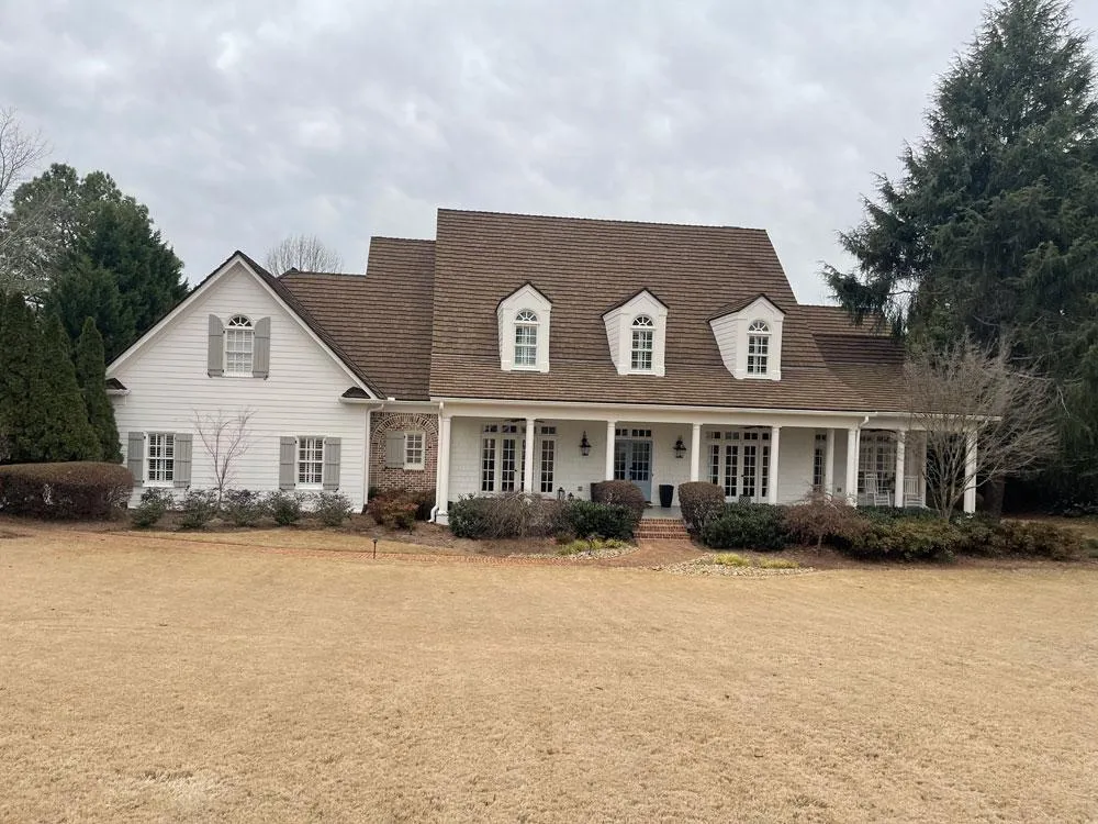 Large traditional home with a mix of white siding and brown brick accents prior to its cohesive exterior repaint.