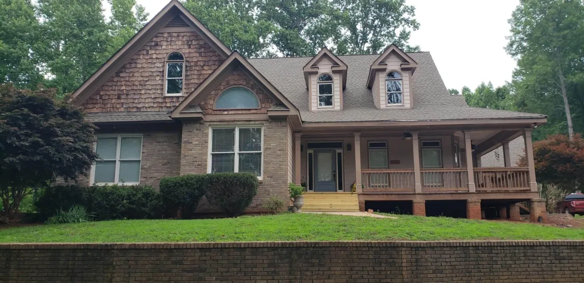 Craftsman-style home with wood shake siding and a covered porch, showing its appearance before being refreshed.