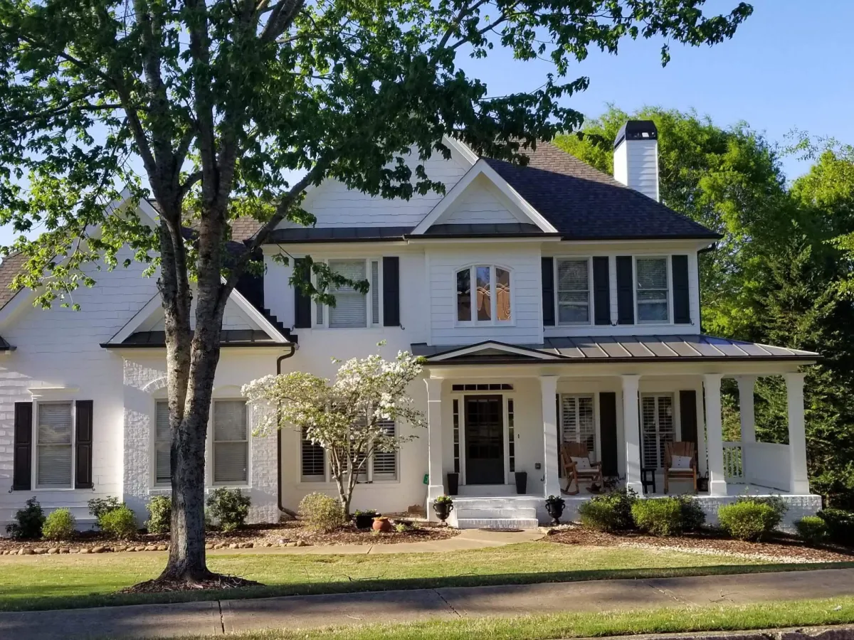 Stunning transformation of a traditional home, now featuring elegant white painted brick and siding with bold black shutters.
