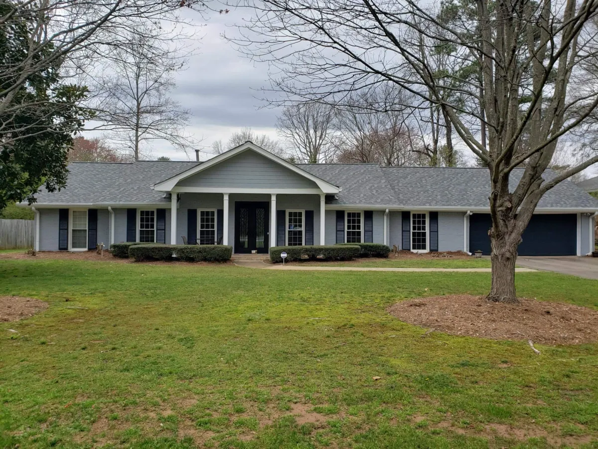 The same brick ranch home, now updated with a stylish gray-blue paint color on the brick and crisp white trim