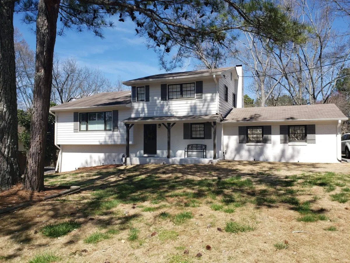 Crisp, modern split-level home completely transformed with a uniform white exterior paint job and black trim details