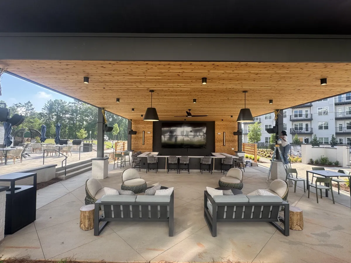 A luxurious covered outdoor patio with a wood-paneled ceiling, comfortable lounge furniture, and an outdoor kitchen.